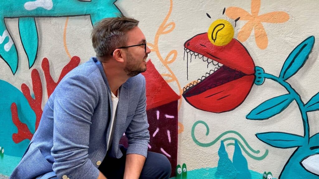 Paweł Lisowski obok eko muralu malowanego w ramach Brave Kids farbami antysmogowymi